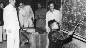 Bác Hồ quan sát một cháu thiếu nhi tập đánh vần khi đến thăm lớp học vỡ lòng Đình Thạch Khối ở phố Hàng Than, Hà Nội (31/12/1958)